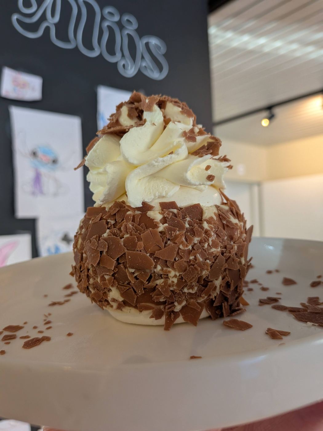 Een coupe met een chocoladebol, slagroom en chocoladeschilfers